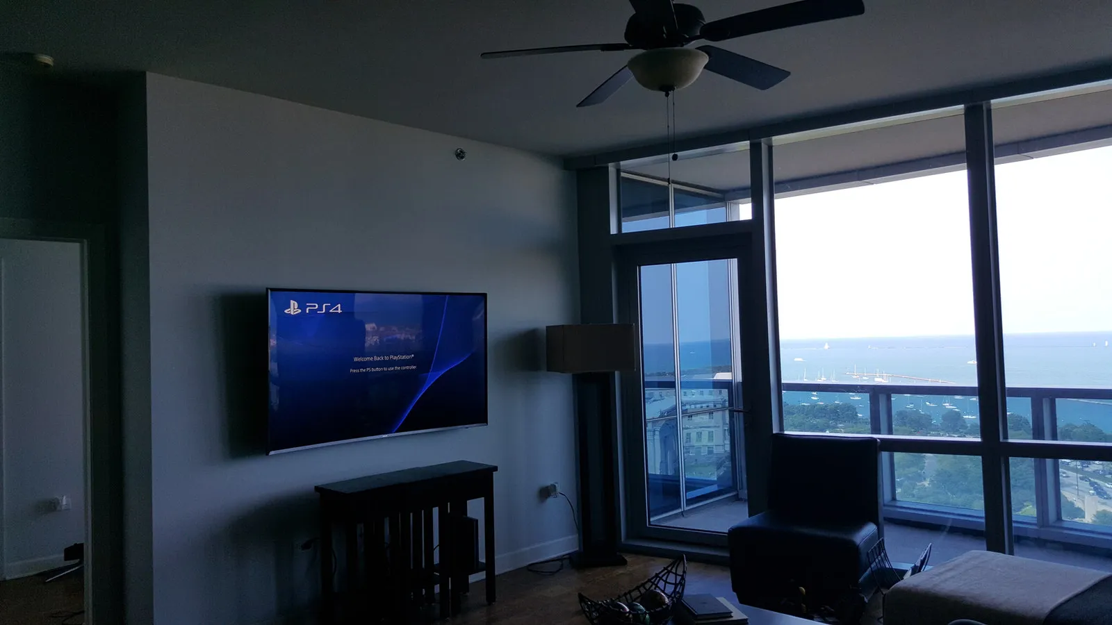Large television wall-mounted in a high-rise condominium living room overlooking Lake Michigan.