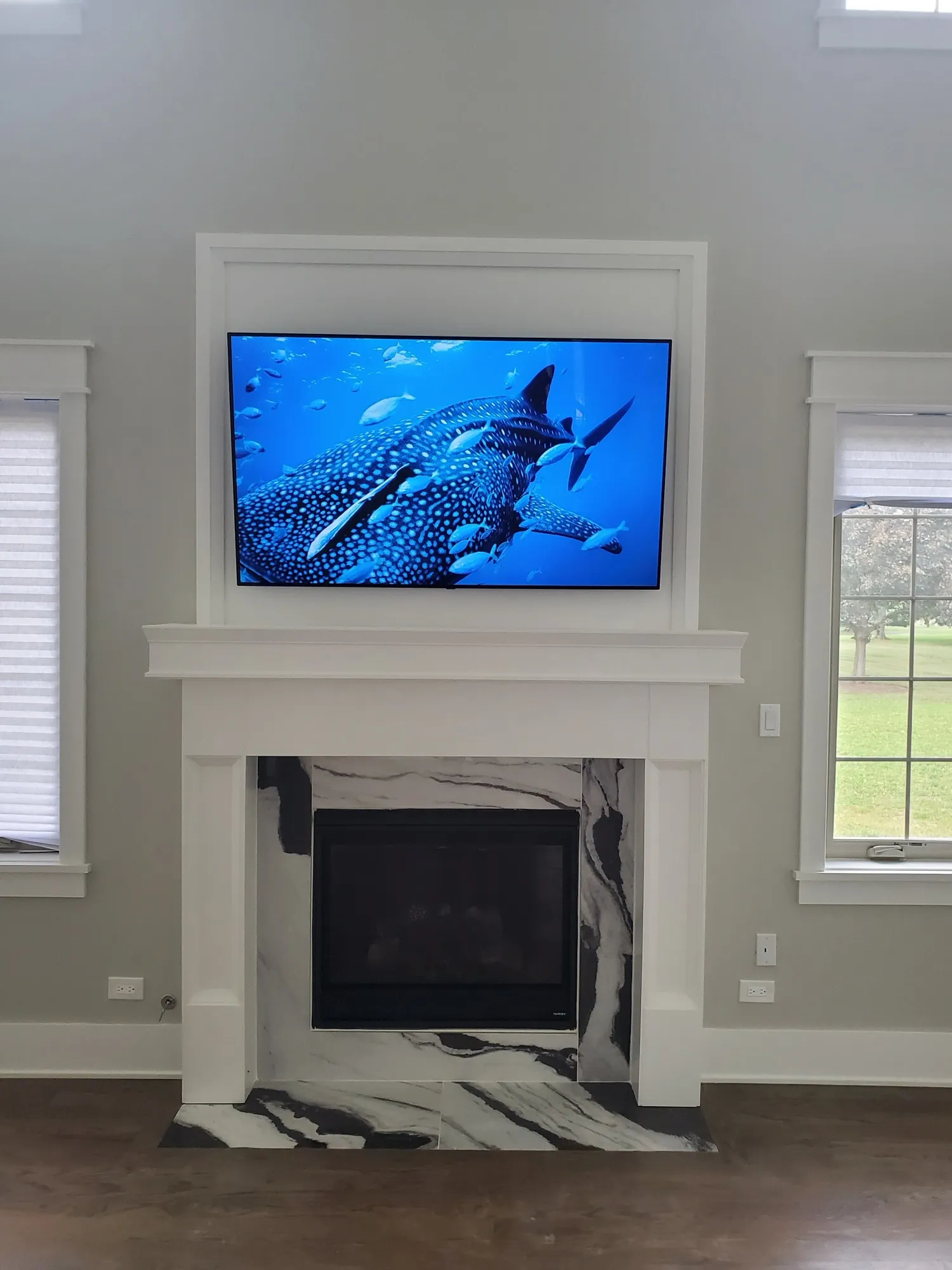 Television recessed into white millwork above a marble-surround fireplace, with no visible cabling.
